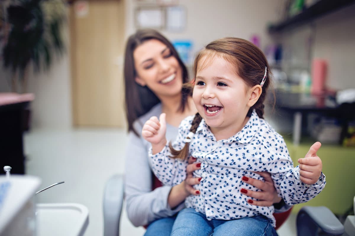 Child in moms lap in dentist office image